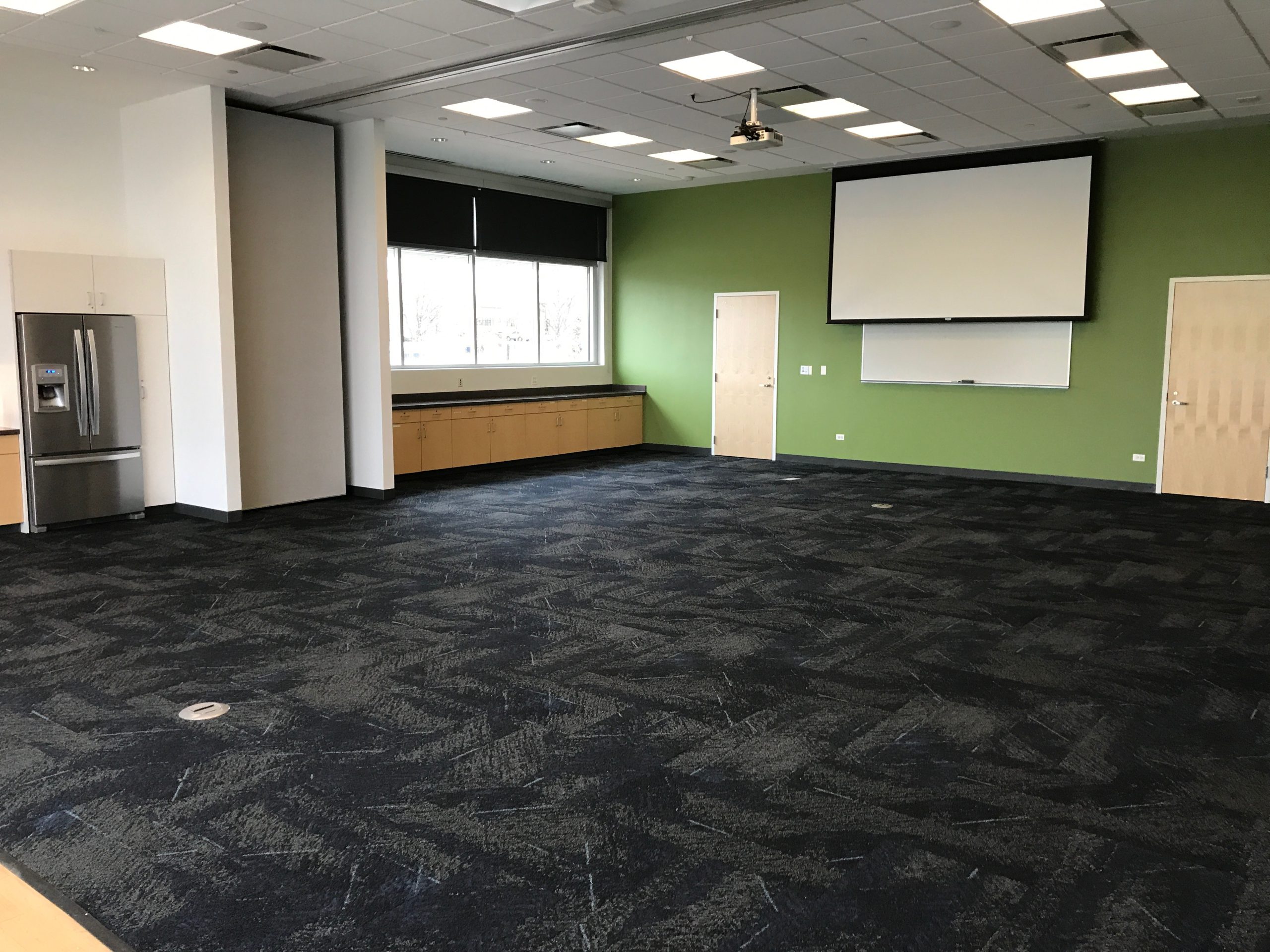 Image of the Aspen Drive meeting room, project screen is down at end of room.