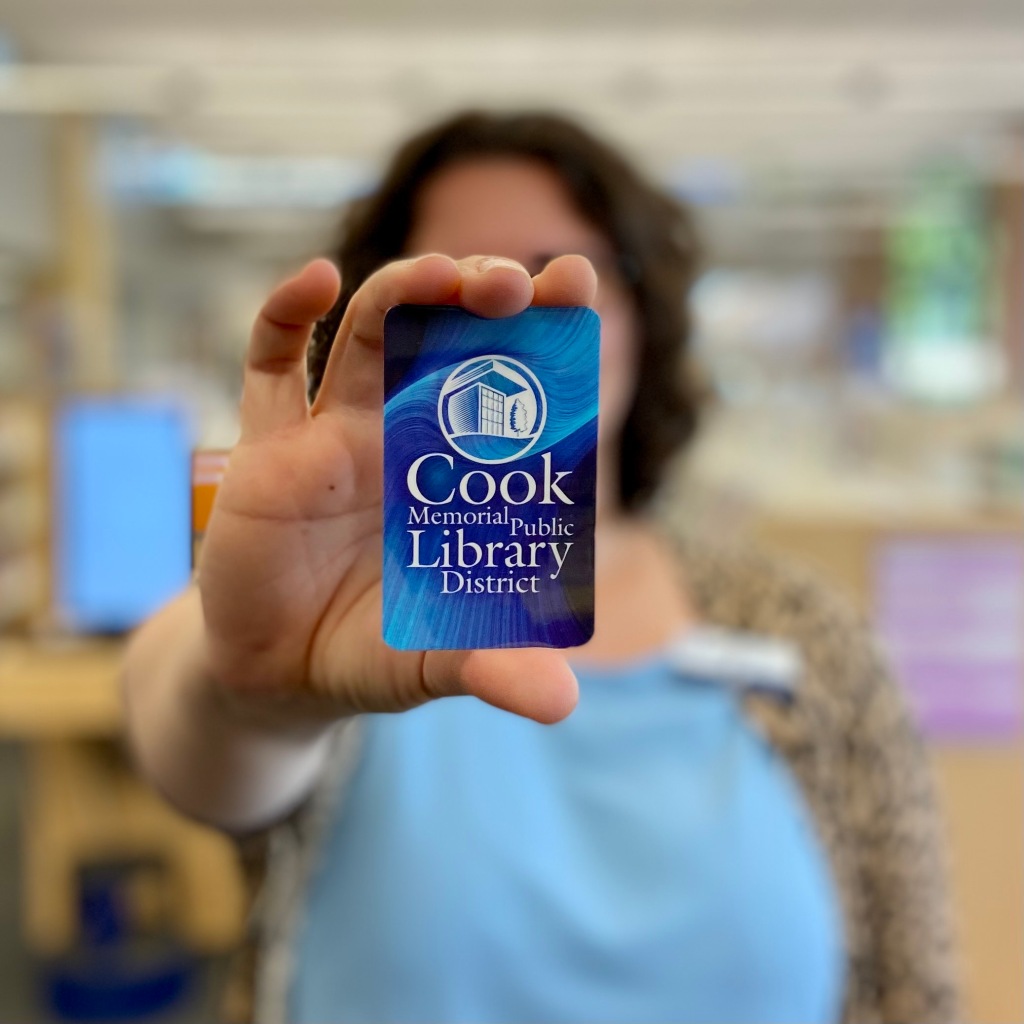 Staff member holding up a Cook Memorial Public Library card to the camera.