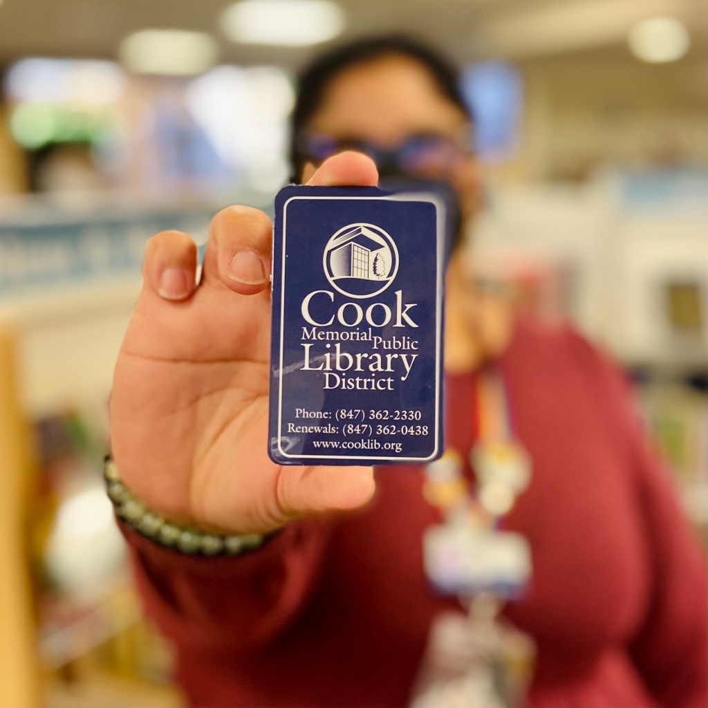 Woman holding up a Cook Memorial Public Library District library card.