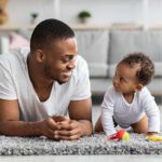 infant and father playing with toys on the carpet