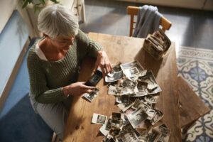Woman with gray hair sorting through black and white photos on a table