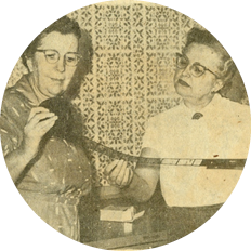 An old newspaper image of two library employees looking at microfilm.