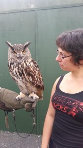 a photo of author Amal El-Mohtar: a Lebanese-Canadian women glances curiosuly at an owl